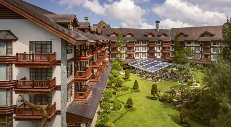 Exterior view of The Manor at Camp John Hay, a luxurious hotel in Baguio City surrounded by lush greenery.